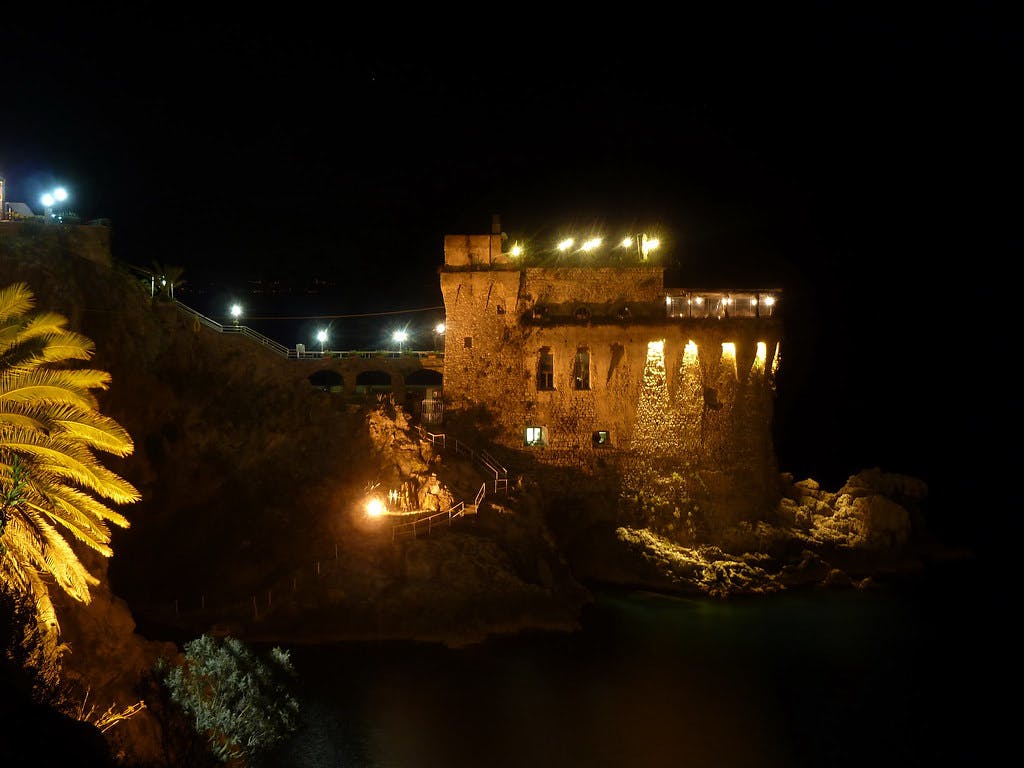Vista de la Torre normanda de Maiori por la noche, iluminada con antorchas.
