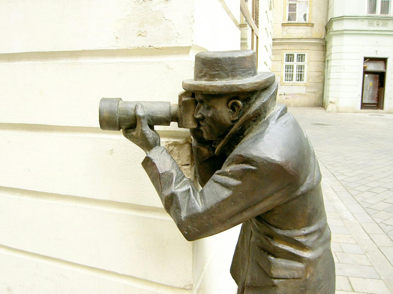 La escultura del papparazzi sacando fotos desde una esquina.